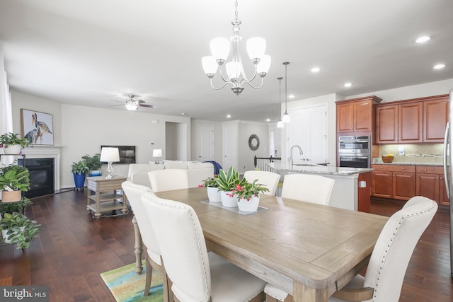 dining area with ceiling fan with notable chandelier, dark hardwood / wood-style floors, and sink