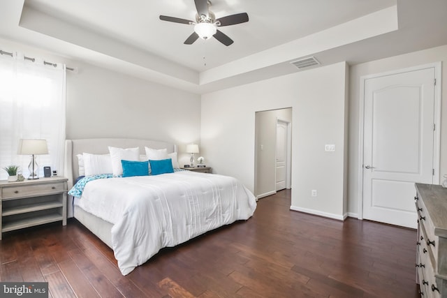 bedroom featuring a tray ceiling, ceiling fan, and dark wood-type flooring