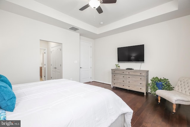 bedroom featuring dark hardwood / wood-style flooring, a tray ceiling, and ceiling fan