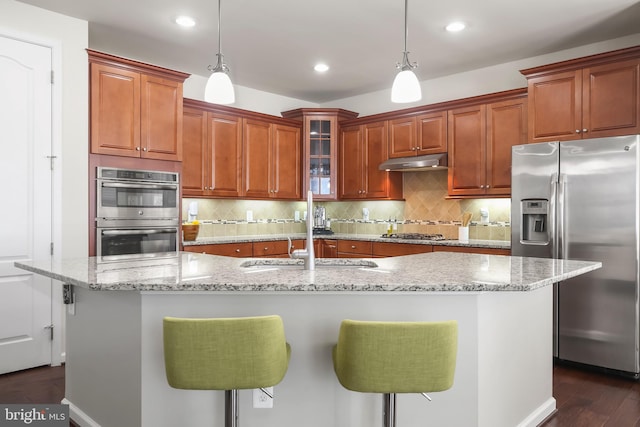 kitchen featuring appliances with stainless steel finishes, pendant lighting, a center island with sink, and a breakfast bar area