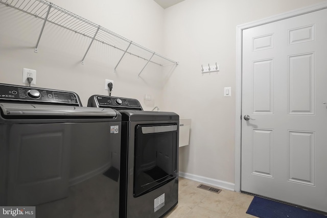 laundry area featuring washer and dryer and light tile patterned flooring