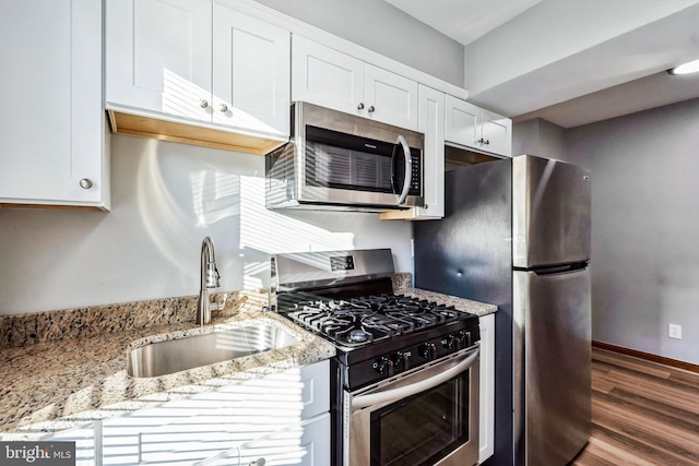 kitchen featuring white cabinetry, sink, light stone counters, and appliances with stainless steel finishes