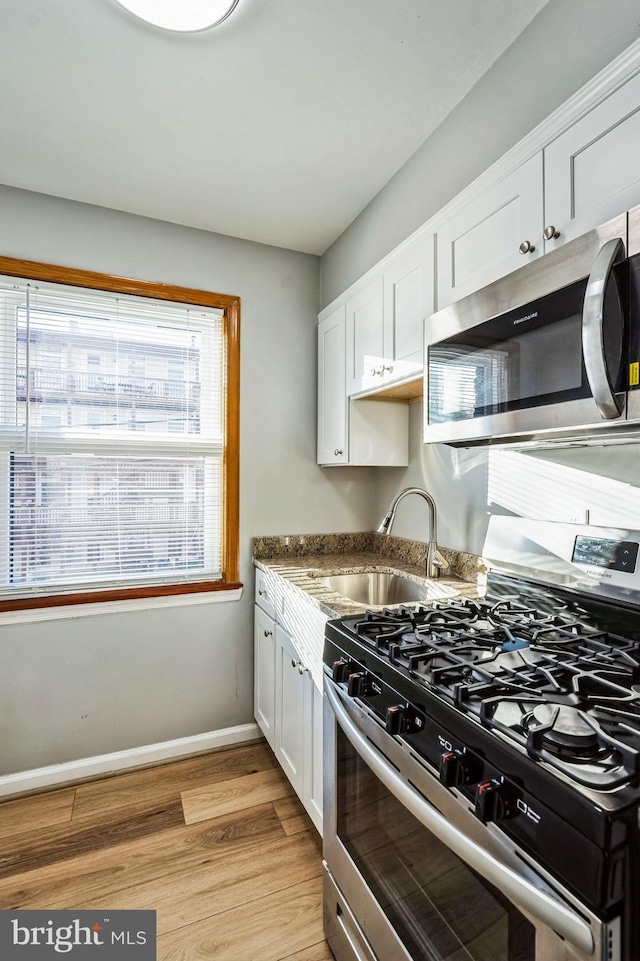 kitchen featuring appliances with stainless steel finishes, light hardwood / wood-style floors, white cabinetry, and sink