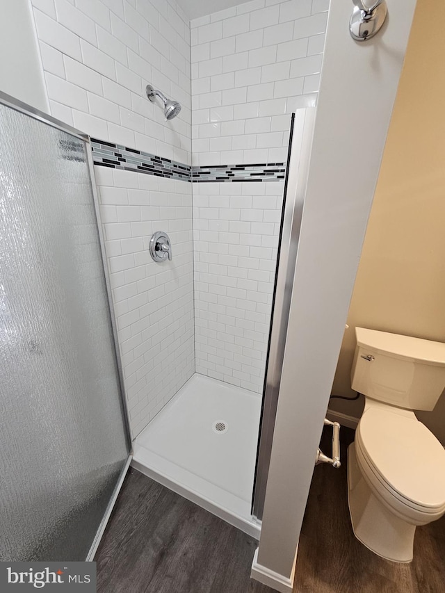 bathroom with toilet, tiled shower, and hardwood / wood-style floors