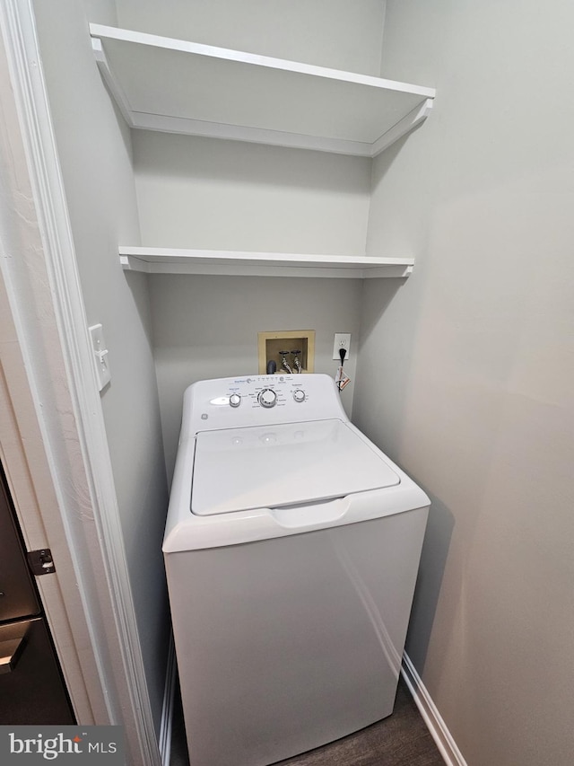 clothes washing area with washer / dryer and dark hardwood / wood-style flooring