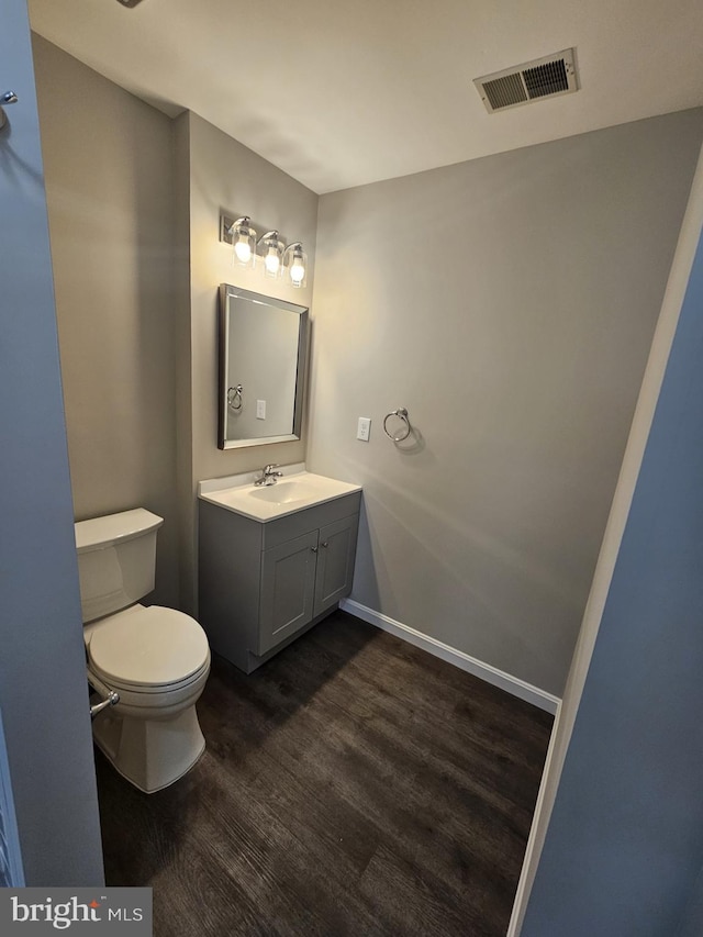 bathroom featuring toilet, vanity, and hardwood / wood-style floors