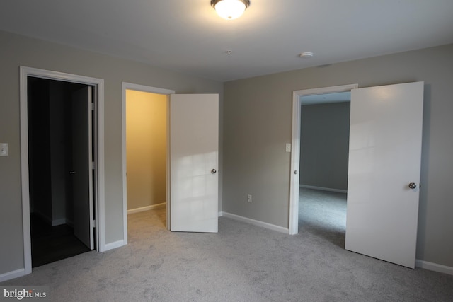 unfurnished bedroom featuring light colored carpet and a spacious closet