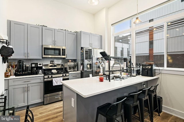 kitchen with gray cabinets, kitchen peninsula, decorative light fixtures, and appliances with stainless steel finishes