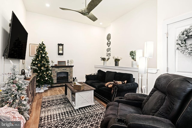 living room with ceiling fan, wood-type flooring, and a fireplace