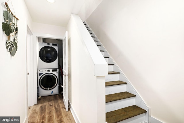 staircase with stacked washer / dryer and wood-type flooring