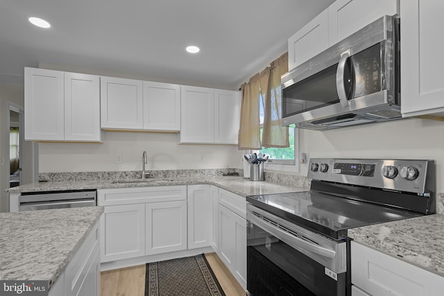 kitchen featuring white cabinetry, sink, light hardwood / wood-style flooring, and appliances with stainless steel finishes