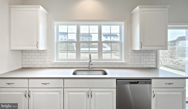 kitchen featuring tasteful backsplash, dishwasher, white cabinets, and sink