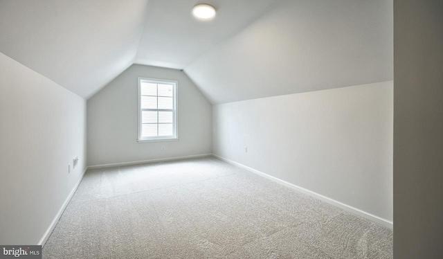 additional living space featuring light colored carpet and vaulted ceiling