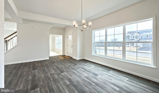 interior space featuring a chandelier, a wealth of natural light, and dark wood-type flooring