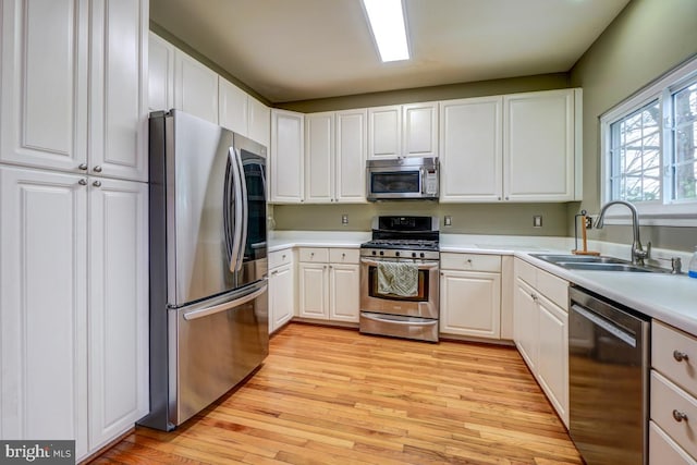 kitchen featuring light wood-type flooring, stainless steel appliances, white cabinetry, and sink