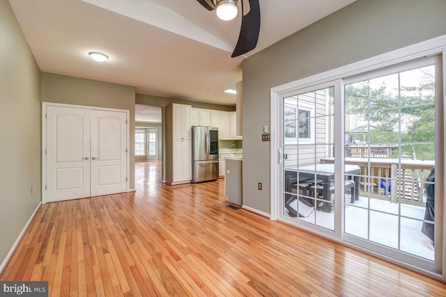 unfurnished living room featuring ceiling fan, light wood-type flooring, and vaulted ceiling