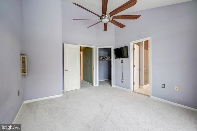 unfurnished bedroom featuring ensuite bath, ceiling fan, high vaulted ceiling, and light carpet