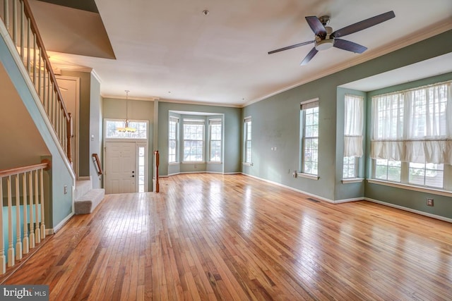 interior space featuring light wood-type flooring, ceiling fan with notable chandelier, and ornamental molding