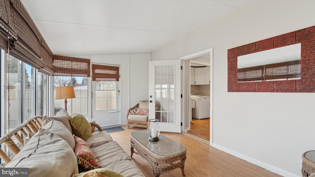 living room featuring lofted ceiling, washer / clothes dryer, and light hardwood / wood-style flooring