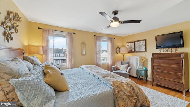 bedroom with ceiling fan, light wood-type flooring, and radiator heating unit