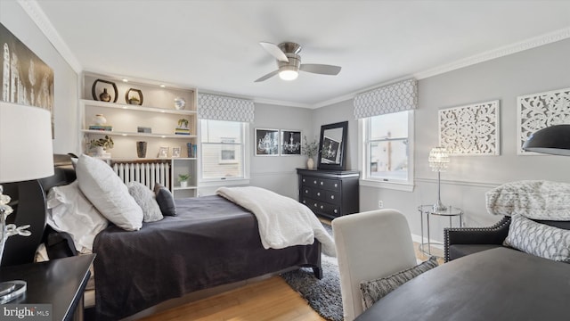 bedroom with hardwood / wood-style floors, ceiling fan, radiator heating unit, and crown molding