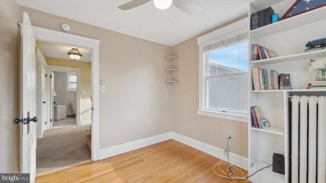 interior space with ceiling fan, radiator heating unit, and hardwood / wood-style floors