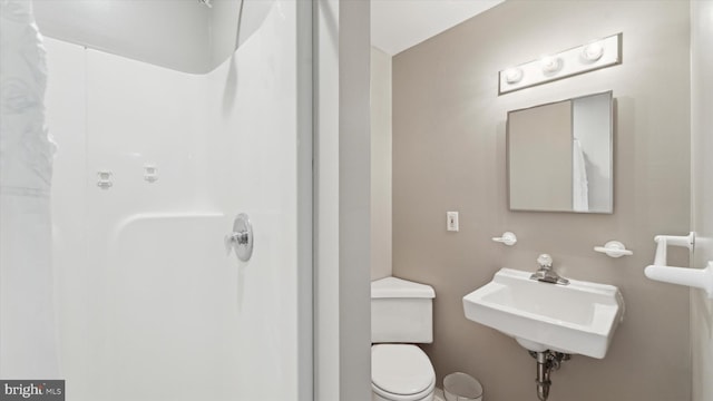 bathroom featuring a shower, toilet, and sink