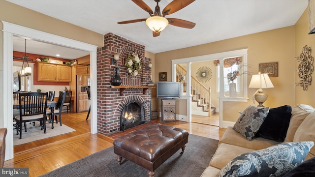 living room featuring ceiling fan, a fireplace, and light hardwood / wood-style floors