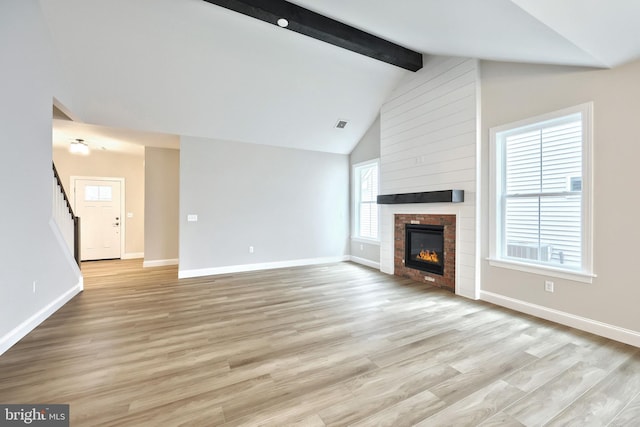 unfurnished living room with light wood-type flooring and lofted ceiling with beams