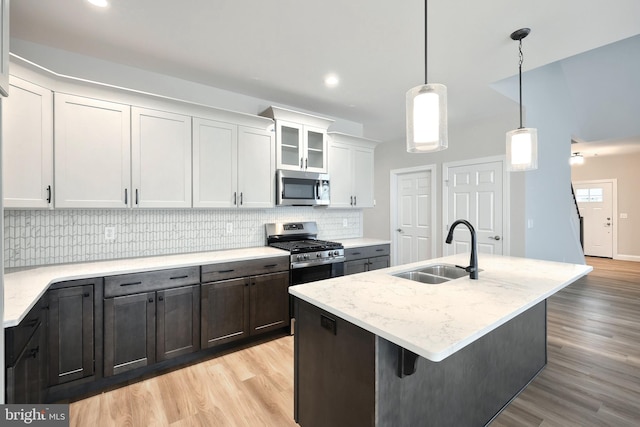 kitchen featuring sink, decorative light fixtures, a center island with sink, white cabinets, and appliances with stainless steel finishes