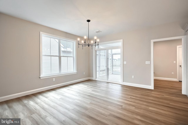 empty room with light hardwood / wood-style flooring and a notable chandelier