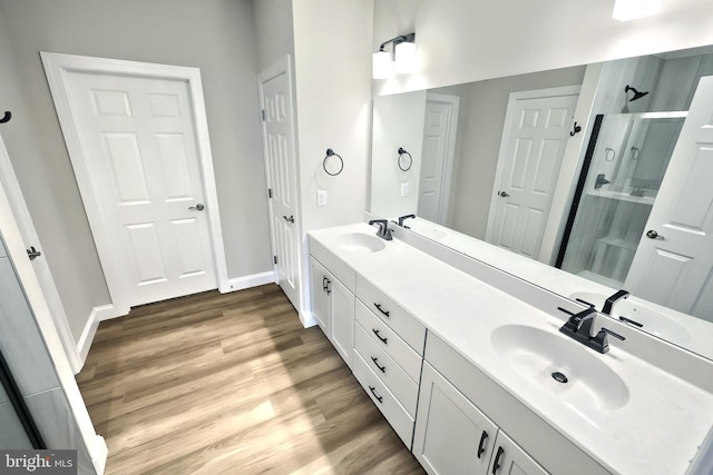 bathroom with hardwood / wood-style floors, vanity, and a shower with door