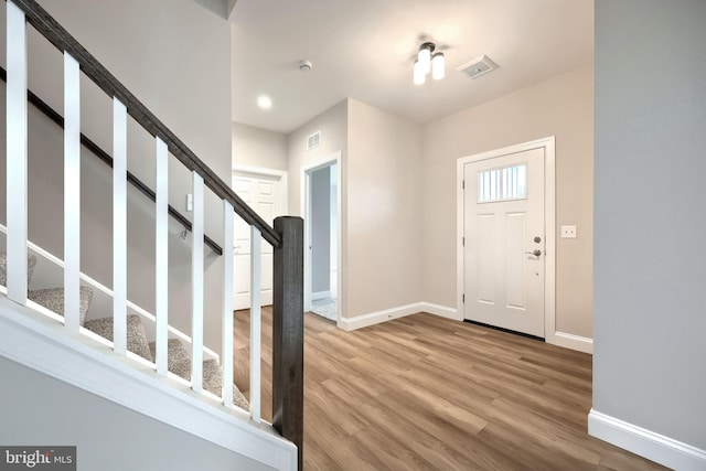 foyer featuring stairway, wood finished floors, visible vents, and baseboards