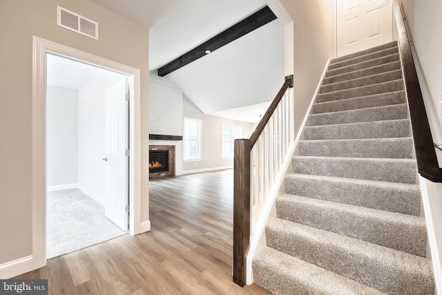 stairway featuring hardwood / wood-style floors and lofted ceiling with beams