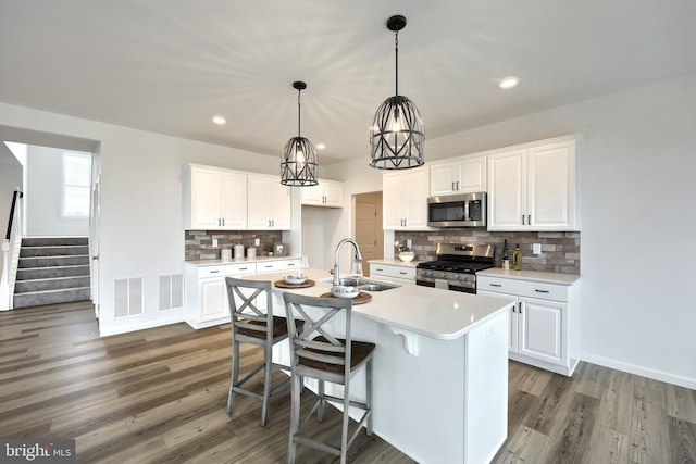 kitchen with stainless steel appliances, white cabinetry, a kitchen island with sink, and sink