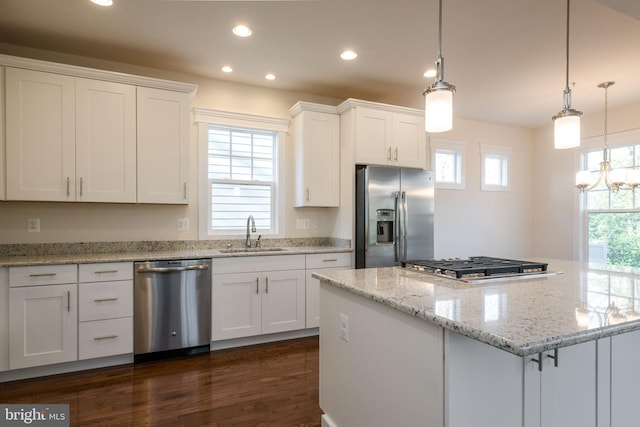 kitchen featuring white cabinetry, stainless steel appliances, a healthy amount of sunlight, decorative light fixtures, and sink