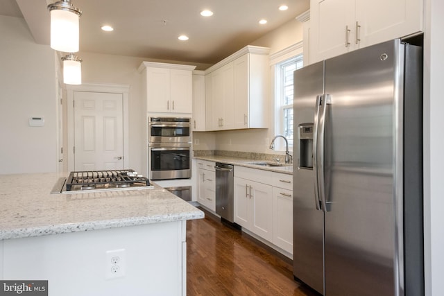 kitchen with decorative light fixtures, sink, white cabinetry, appliances with stainless steel finishes, and light stone counters