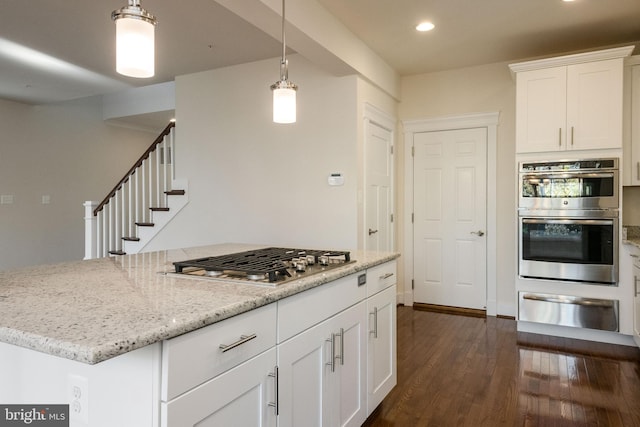 kitchen with white cabinetry, appliances with stainless steel finishes, dark hardwood / wood-style flooring, hanging light fixtures, and light stone countertops