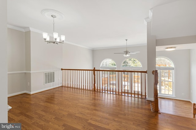 spare room featuring dark hardwood / wood-style flooring, ceiling fan with notable chandelier, and ornamental molding