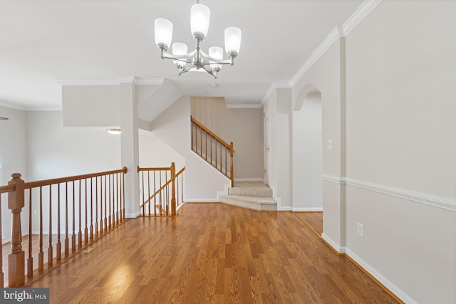 hallway featuring wood-type flooring, a notable chandelier, and ornamental molding