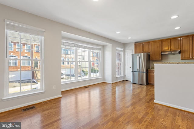 kitchen featuring a wealth of natural light, stainless steel refrigerator, and light hardwood / wood-style flooring