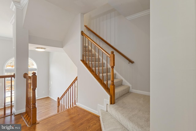 stairway featuring wood-type flooring, vaulted ceiling, and ornamental molding