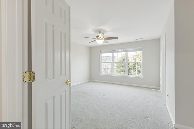 empty room featuring ceiling fan and light carpet