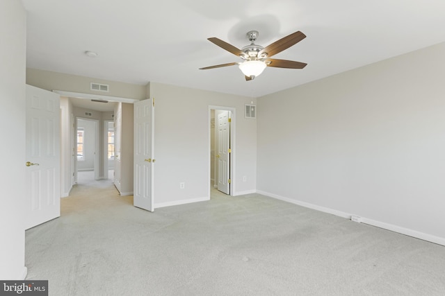 unfurnished bedroom featuring ceiling fan, light colored carpet, a closet, and a spacious closet