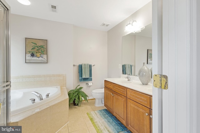 bathroom featuring tiled tub, toilet, vanity, and tile patterned flooring