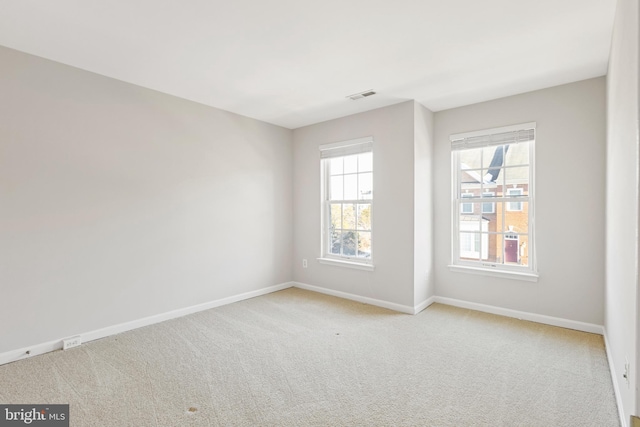 spare room featuring light colored carpet and a wealth of natural light