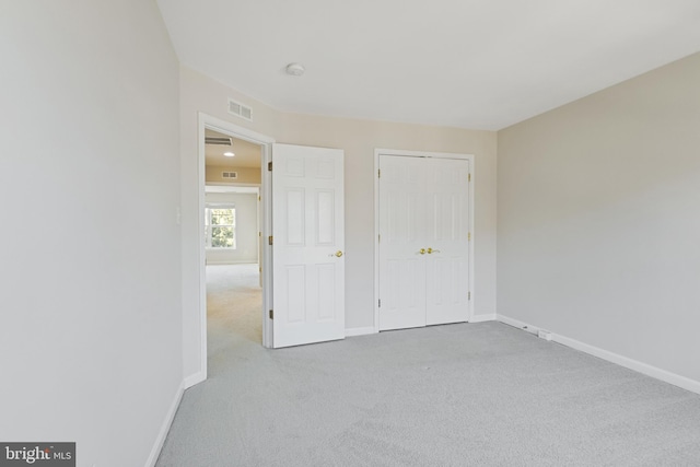 unfurnished bedroom featuring light colored carpet and a closet