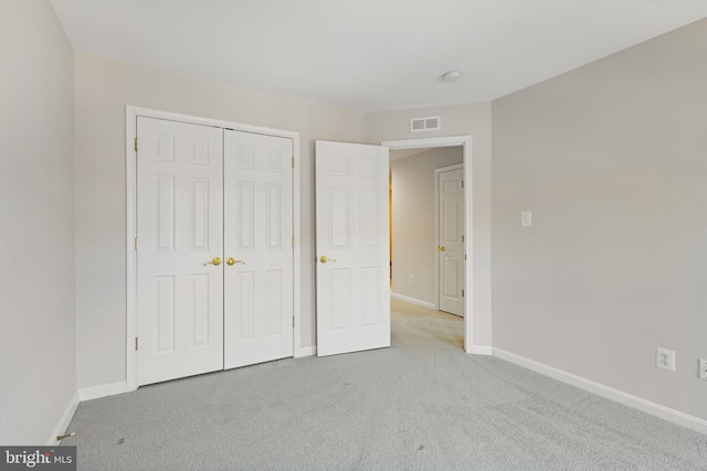 unfurnished bedroom with light colored carpet and a closet