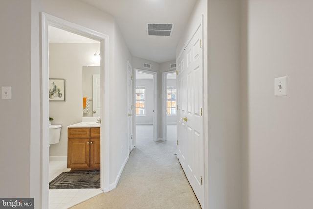 hall featuring light colored carpet and sink