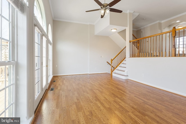 empty room featuring ceiling fan, light wood-type flooring, a wealth of natural light, and crown molding